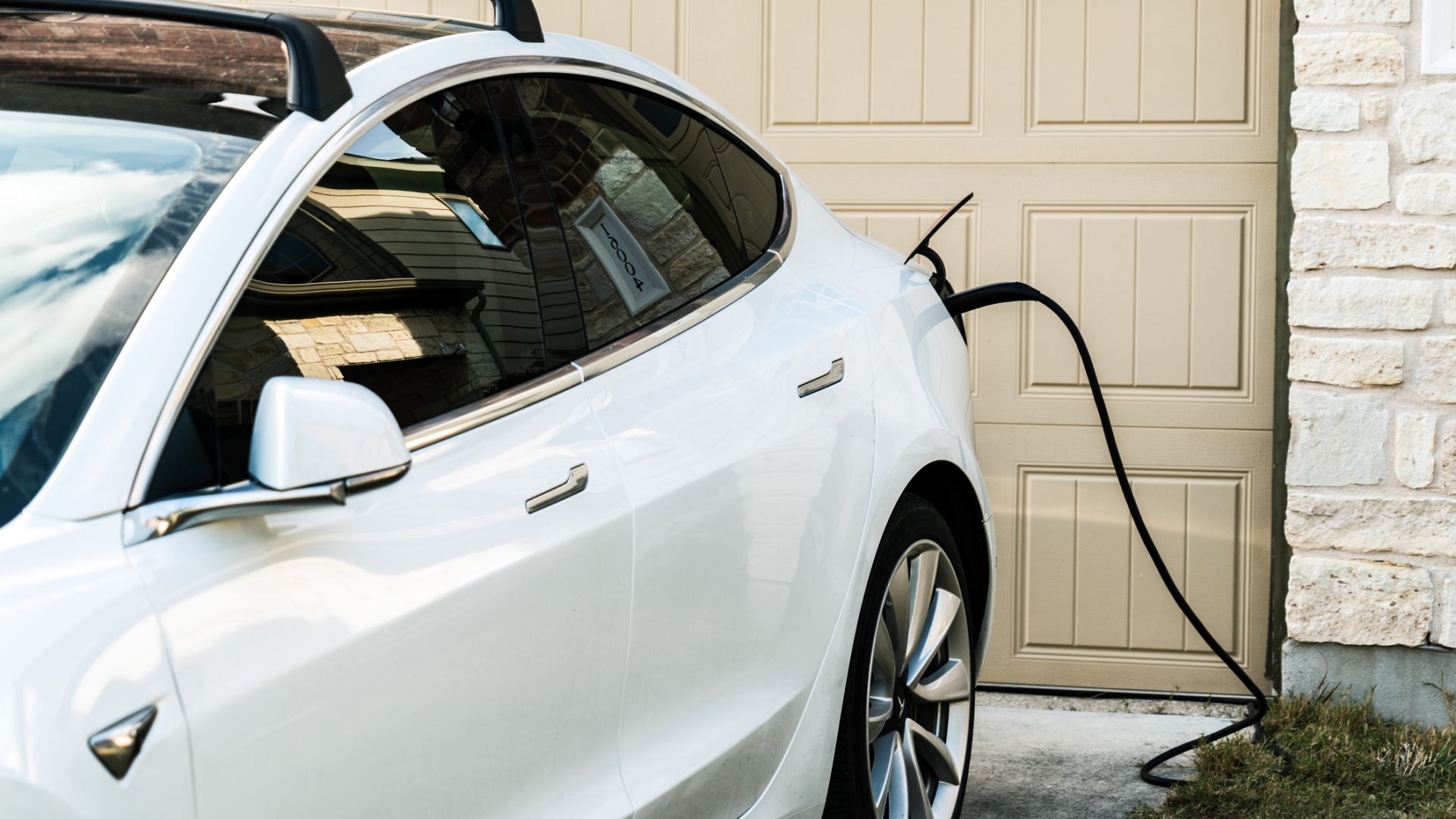 Tesla Model 3 charging in front of a house